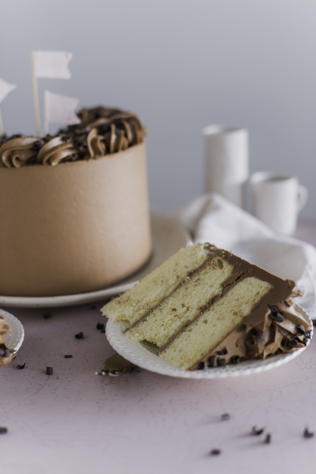 A slice of Yellow Cake with the full cake next to it on a plate.