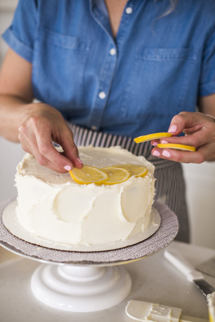 Woman adding lemon to the top of a cake.