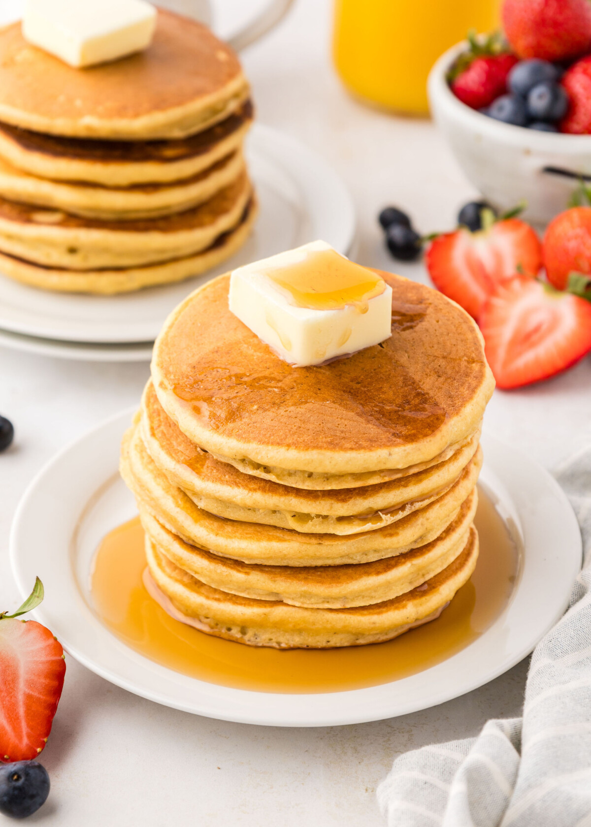 A stack of pancakes on a plate with butter and syrup.