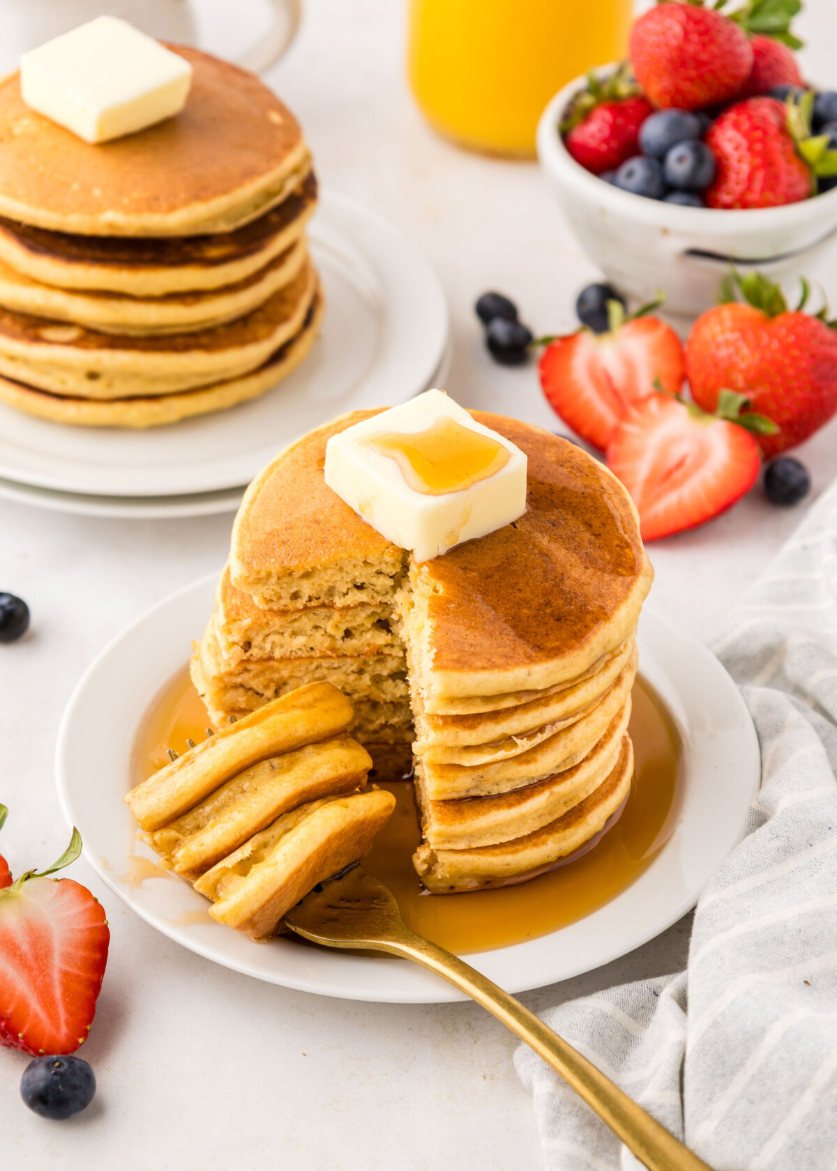 A stack of pancakes with syrup and fruit.