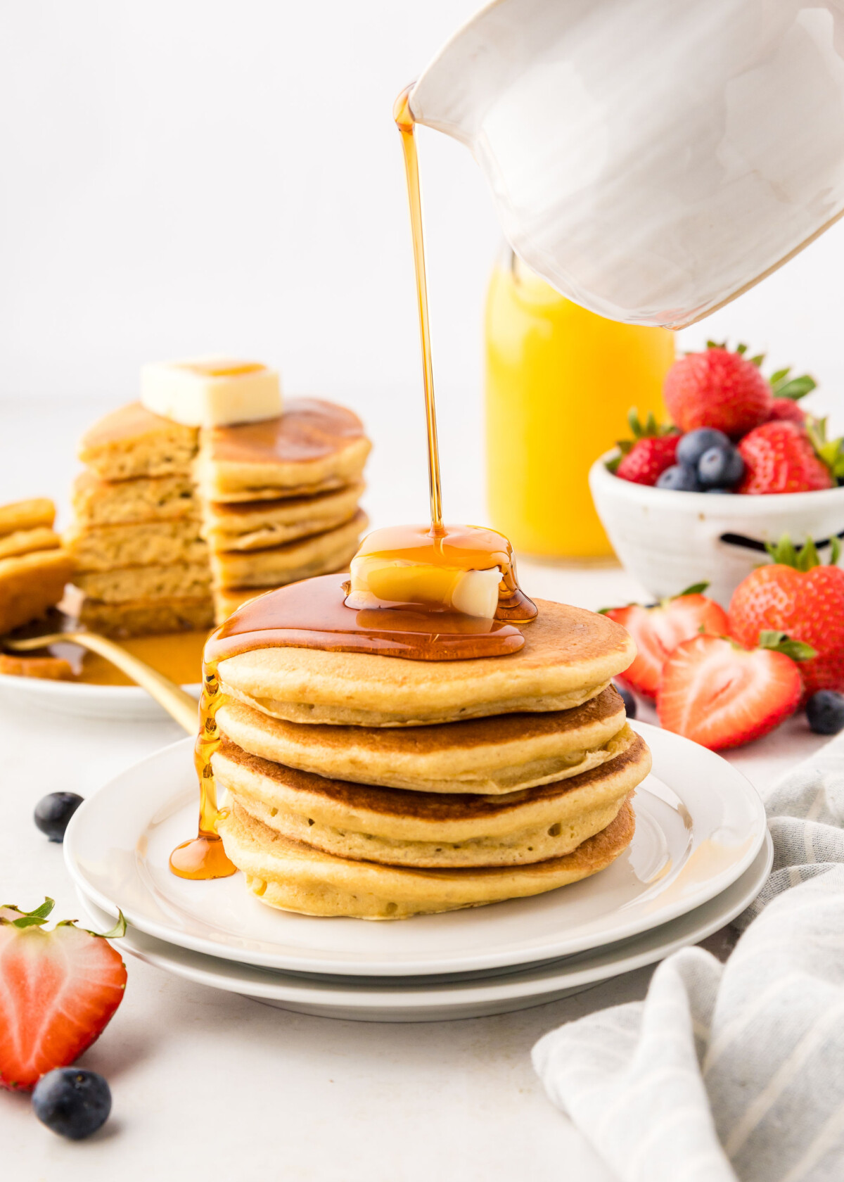 Stack of pancakes with syrup being poured on top.