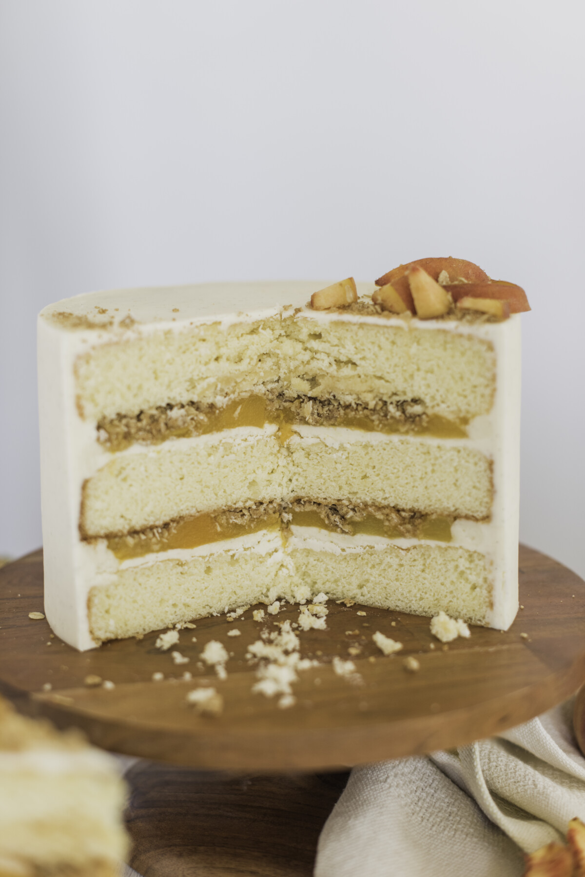 A peach crisp cake on a cake stand with half of the cake cut out.