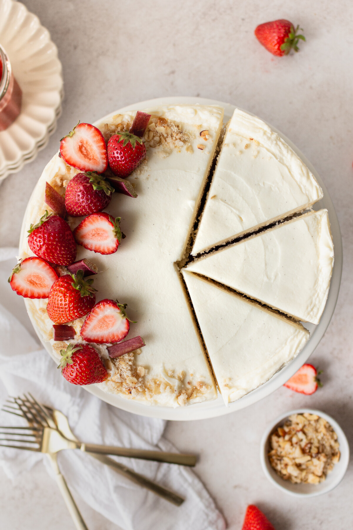 Overhead shot of a cake with strawberries on it with slices cut into it.