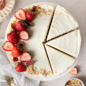 Overhead shot of a cake with strawberries on it with slices cut into it.