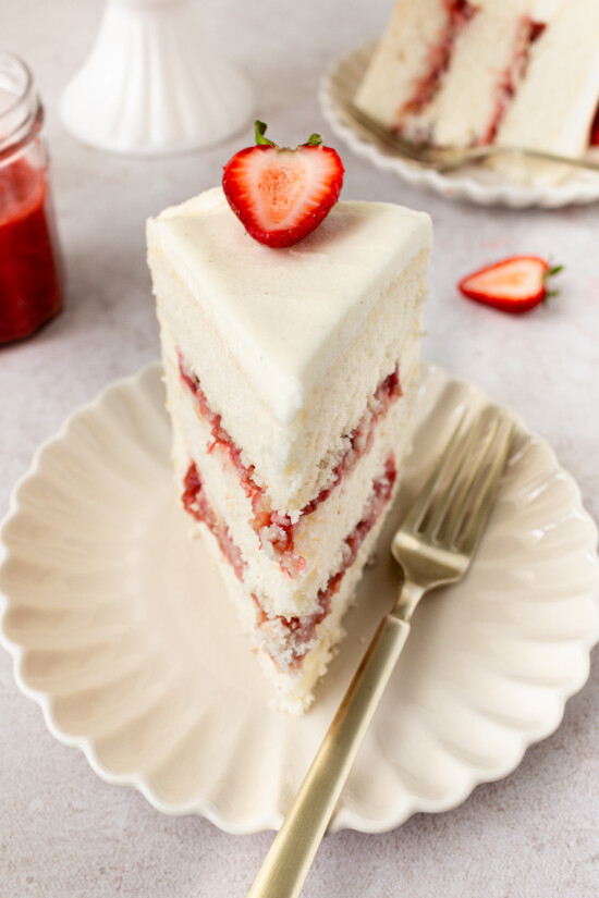 A slice of strawberry rhubarb cake on a plate with a fork.