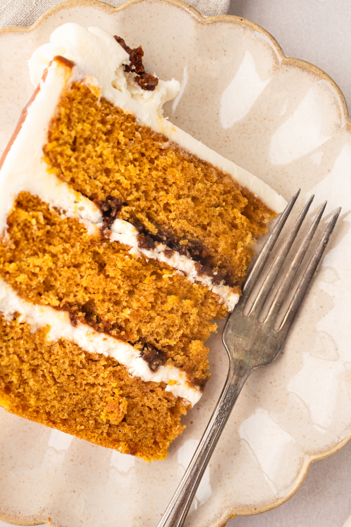 A three layer cake slice on a plate with a fork. 