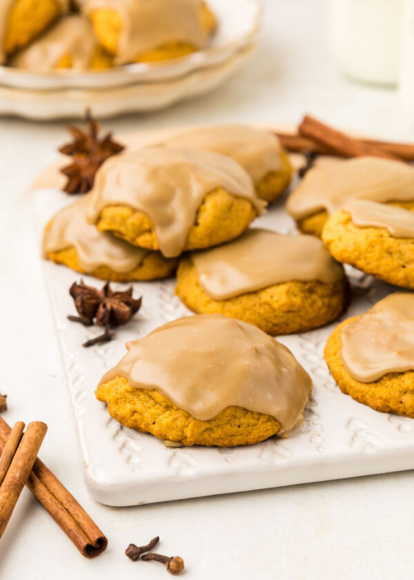 Pumpkin cookies on a cutting board with cinnamon sticks.