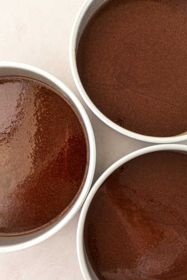 Chocolate cake batter in cake pans.