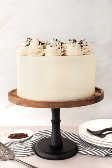 A chocolate cake with vanilla buttercream on a cake stand.