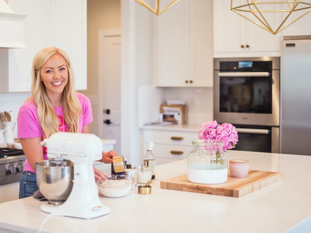 Female baker incorporating ingredients into mixing bowl to make layered cake and buttercream