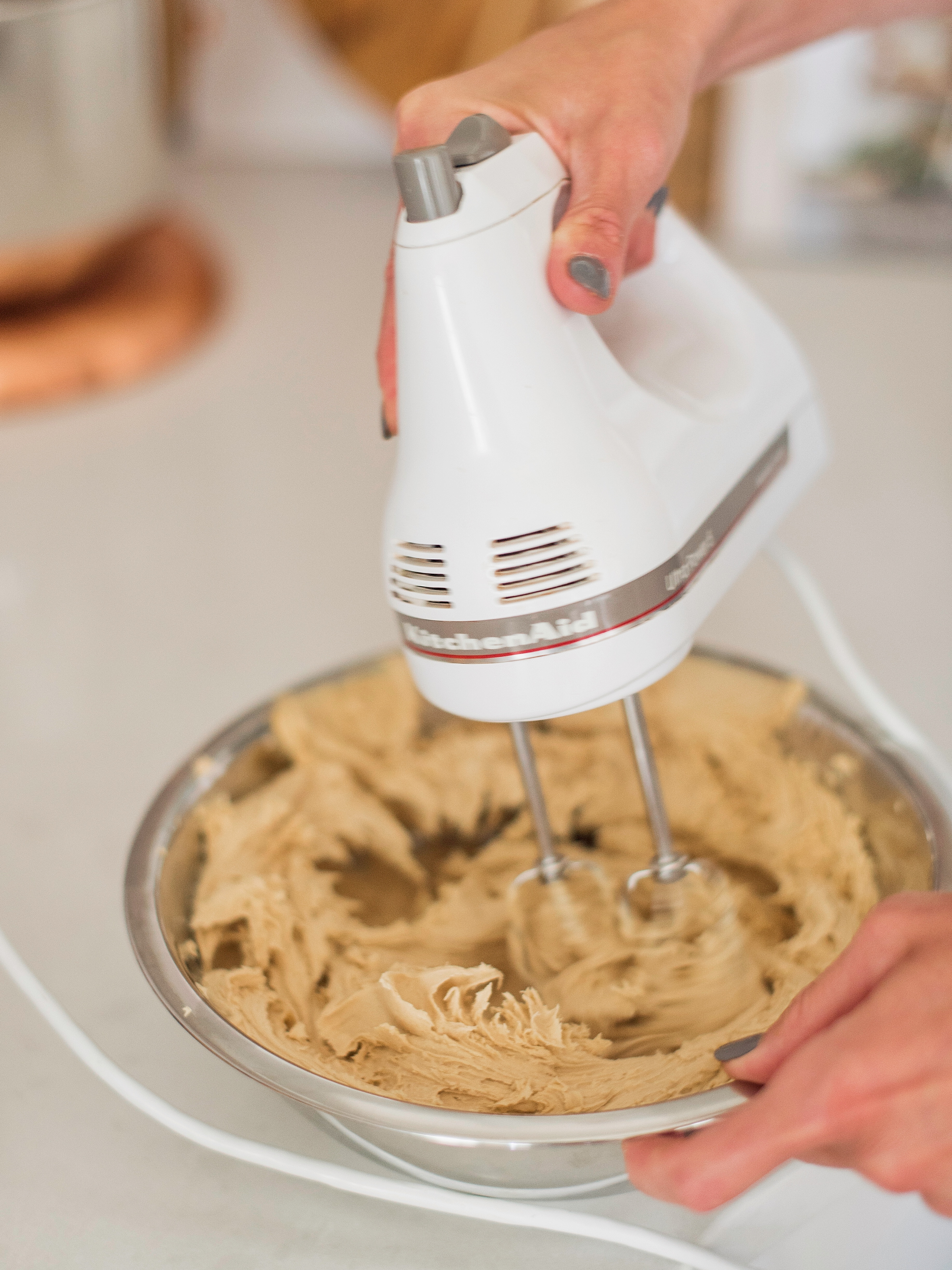 Woman mixing buttercream with a hand mixer.