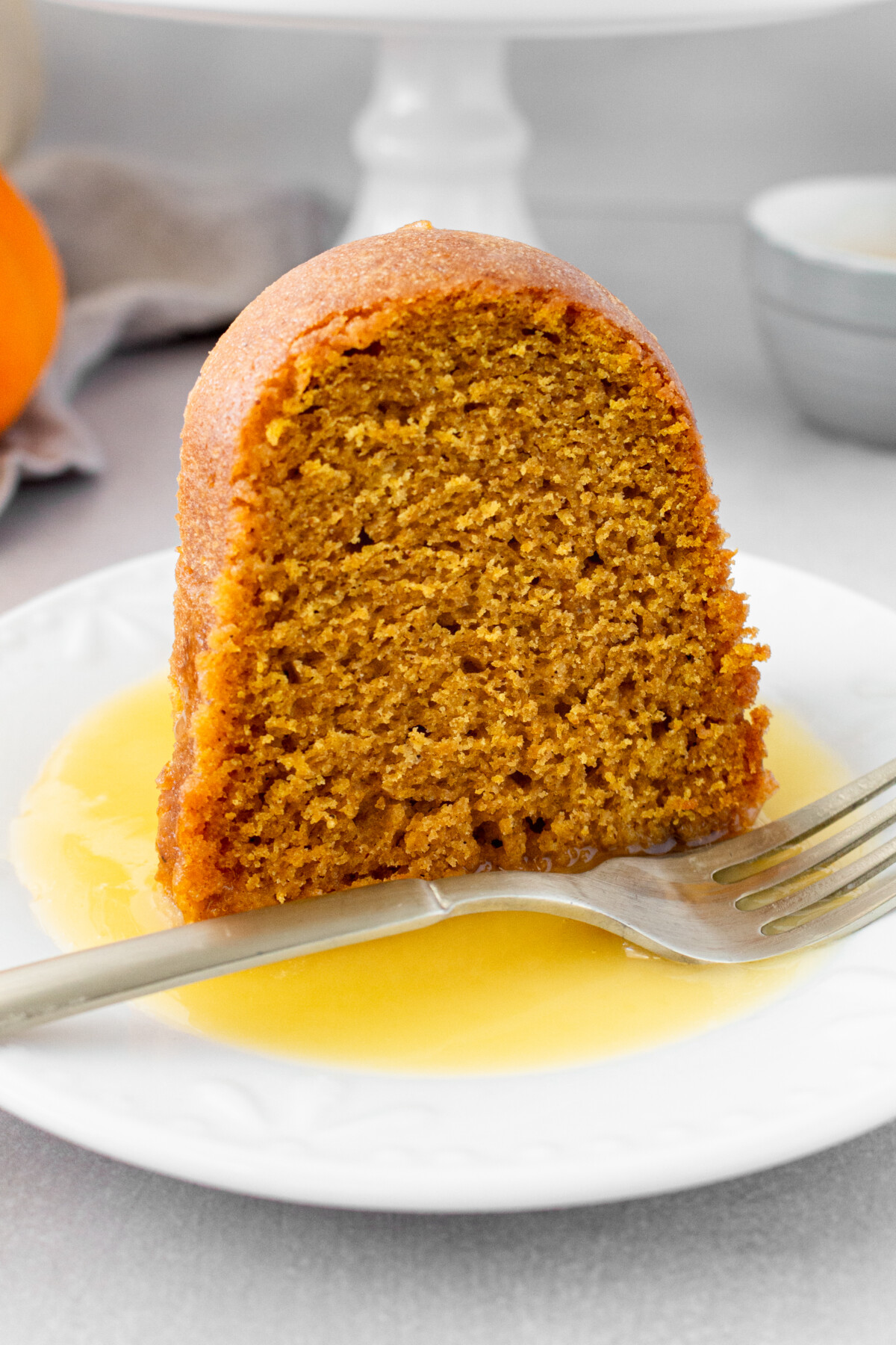 A slice of pumpkin cake on a plate with a fork.