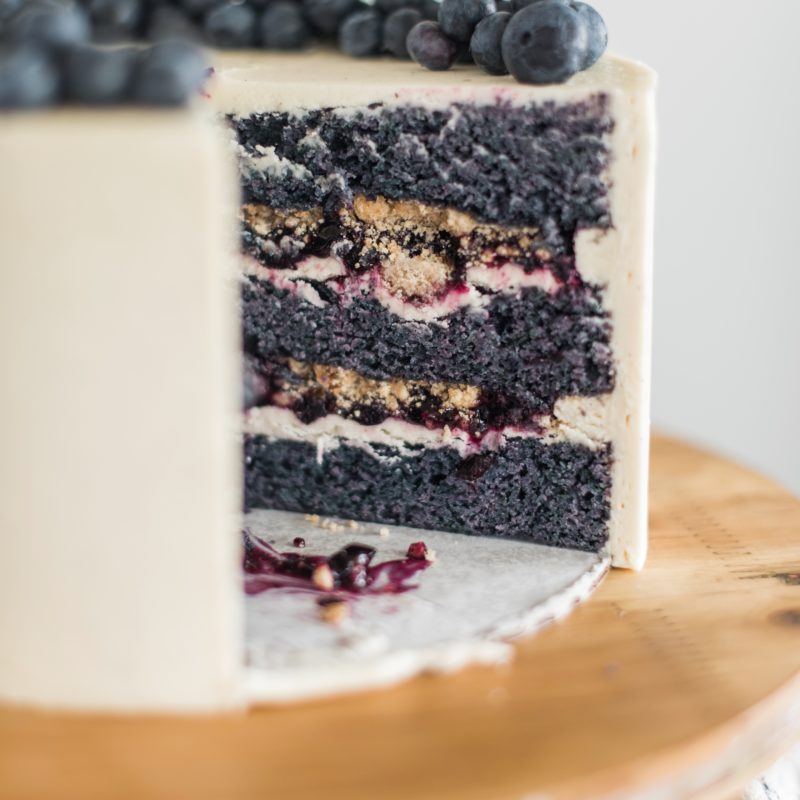 Blueberry Cobbler Cake - blueberry cake layers with vanilla bean buttercream, blueberry compote and cobbler crunch filling. #cakebycourtney #blueberrycobblercake #blueberrycobbler #blueberrycake #blueberrycakerecipe #bestblueberrycakerecipe #blueberrycobblerrecipe #summerdessertrecipes #summercakerecipes #bestsummercakes #bestblueberrydesserts #summercake #howtomakebuttercreamfrosting #howtocakeit