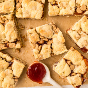 Peanut butter and jelly bars cut into squares on a cutting board.