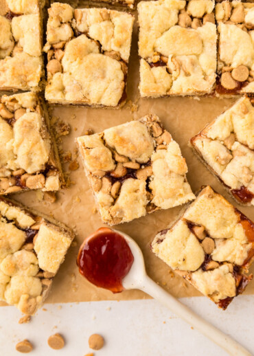 Peanut butter and jelly bars cut into squares on a cutting board.