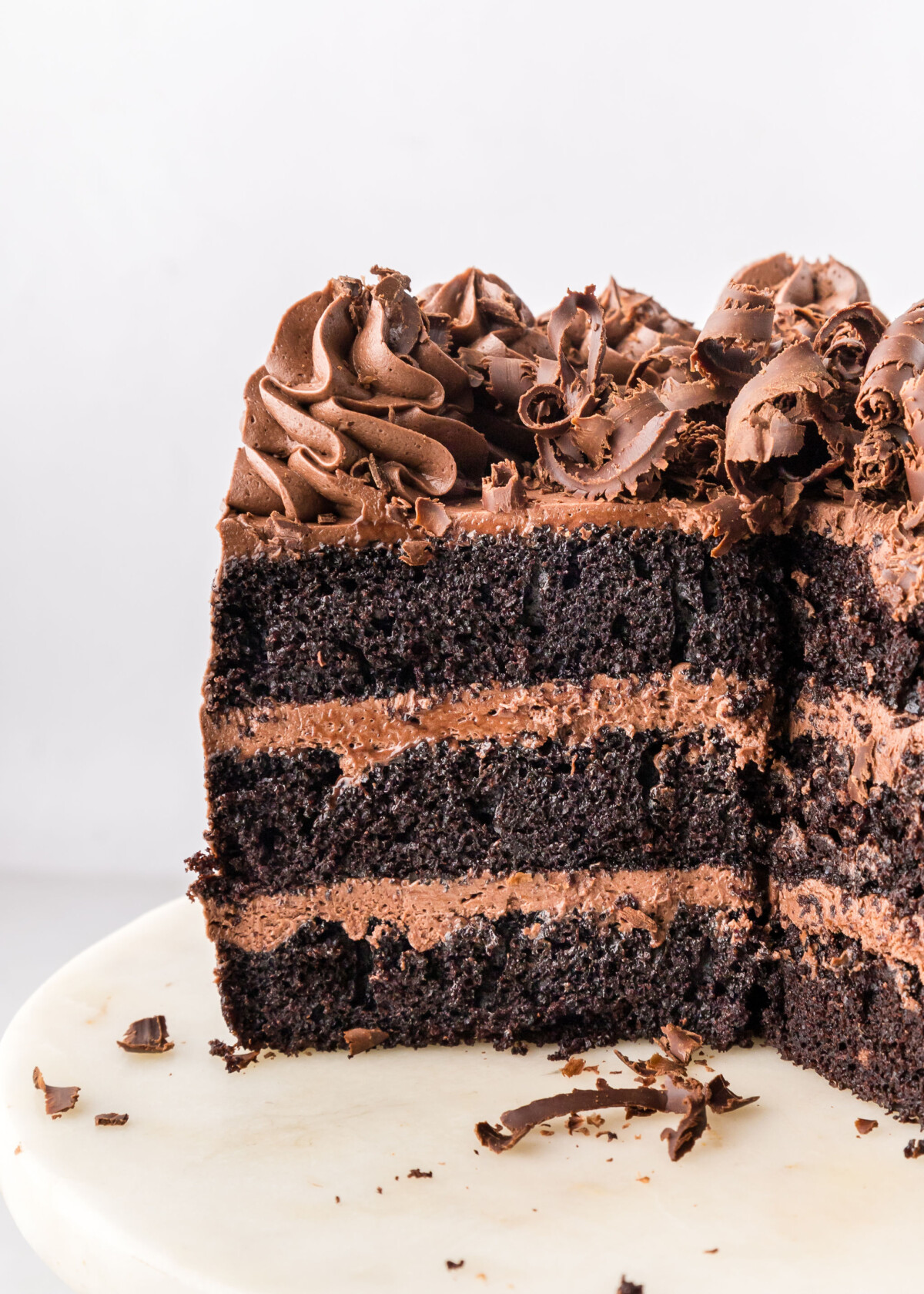 A three layer chocolate cake on a cake stand.