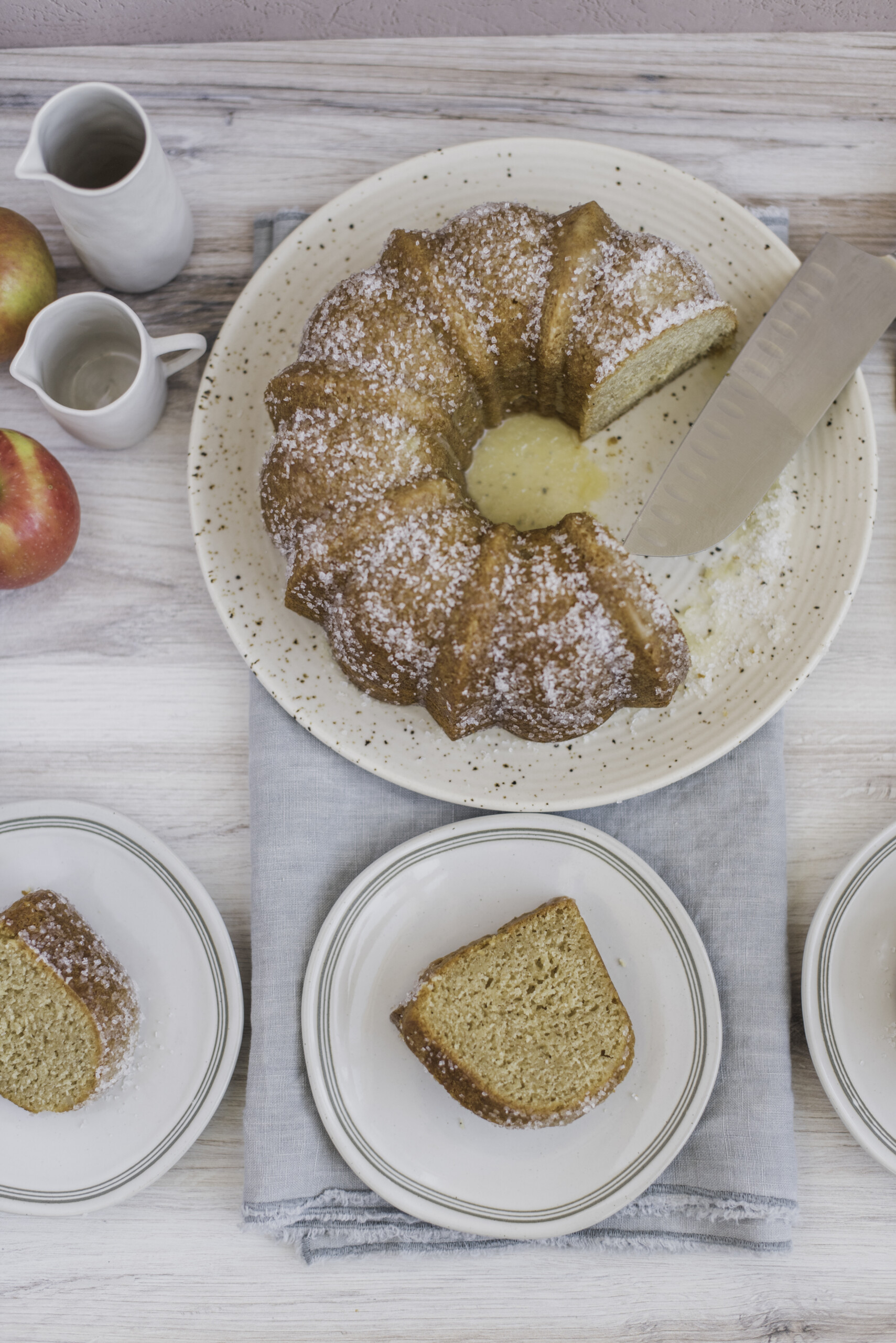 A bundt cake on a plate with slices of the cake on small plates next to it.