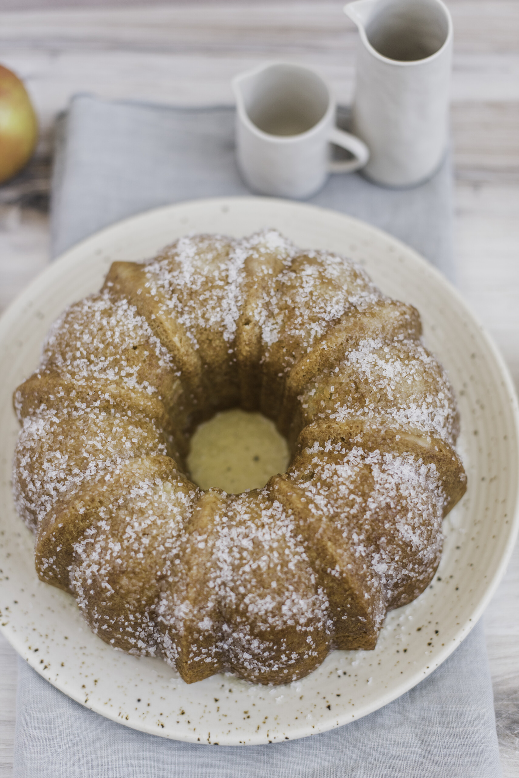 A bundt cake on a plate with cups next to it.