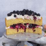 A two layer cake on a cake stand, cut in half to show the filling