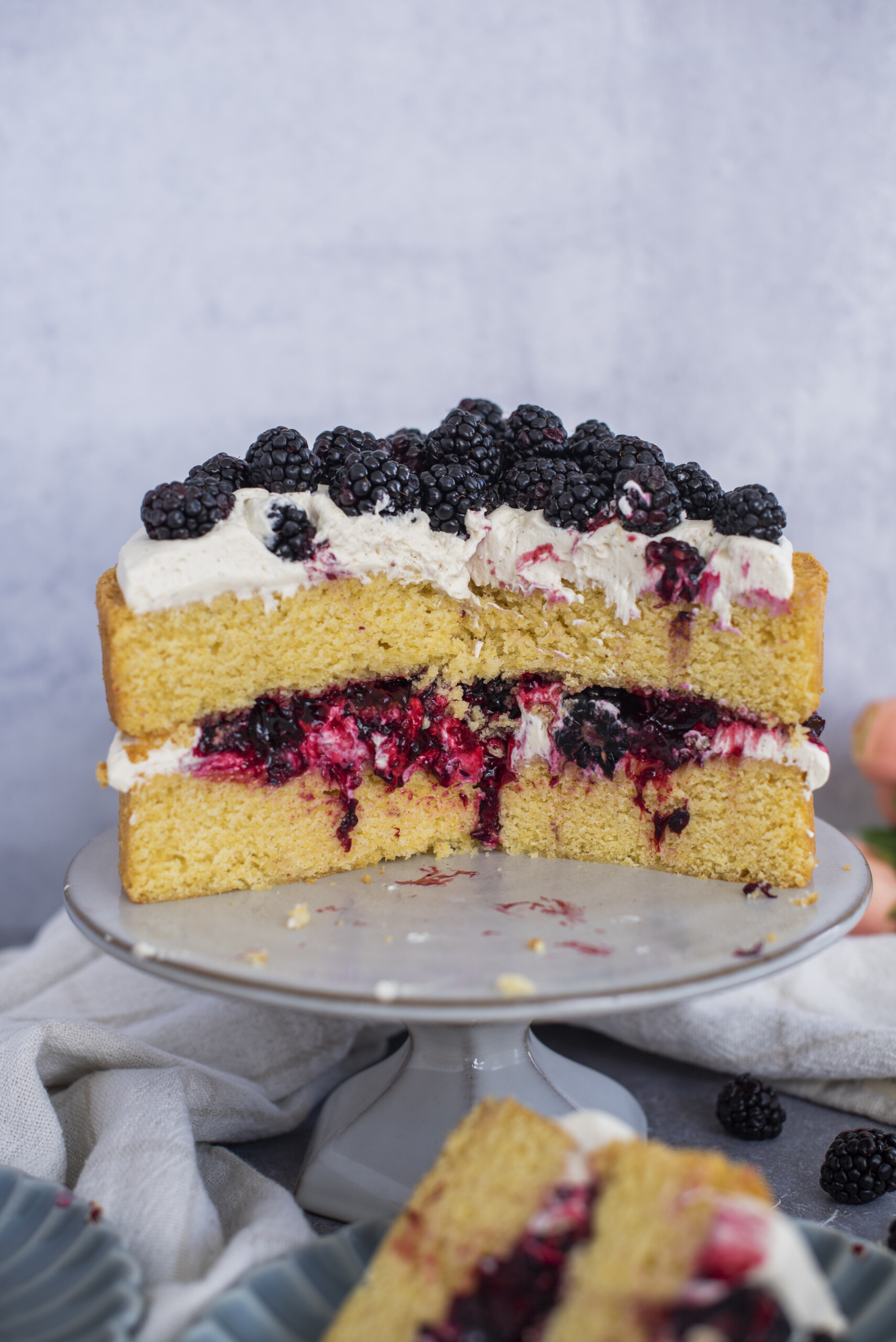 A two layer cake on a cake stand, cut in half to show the filling