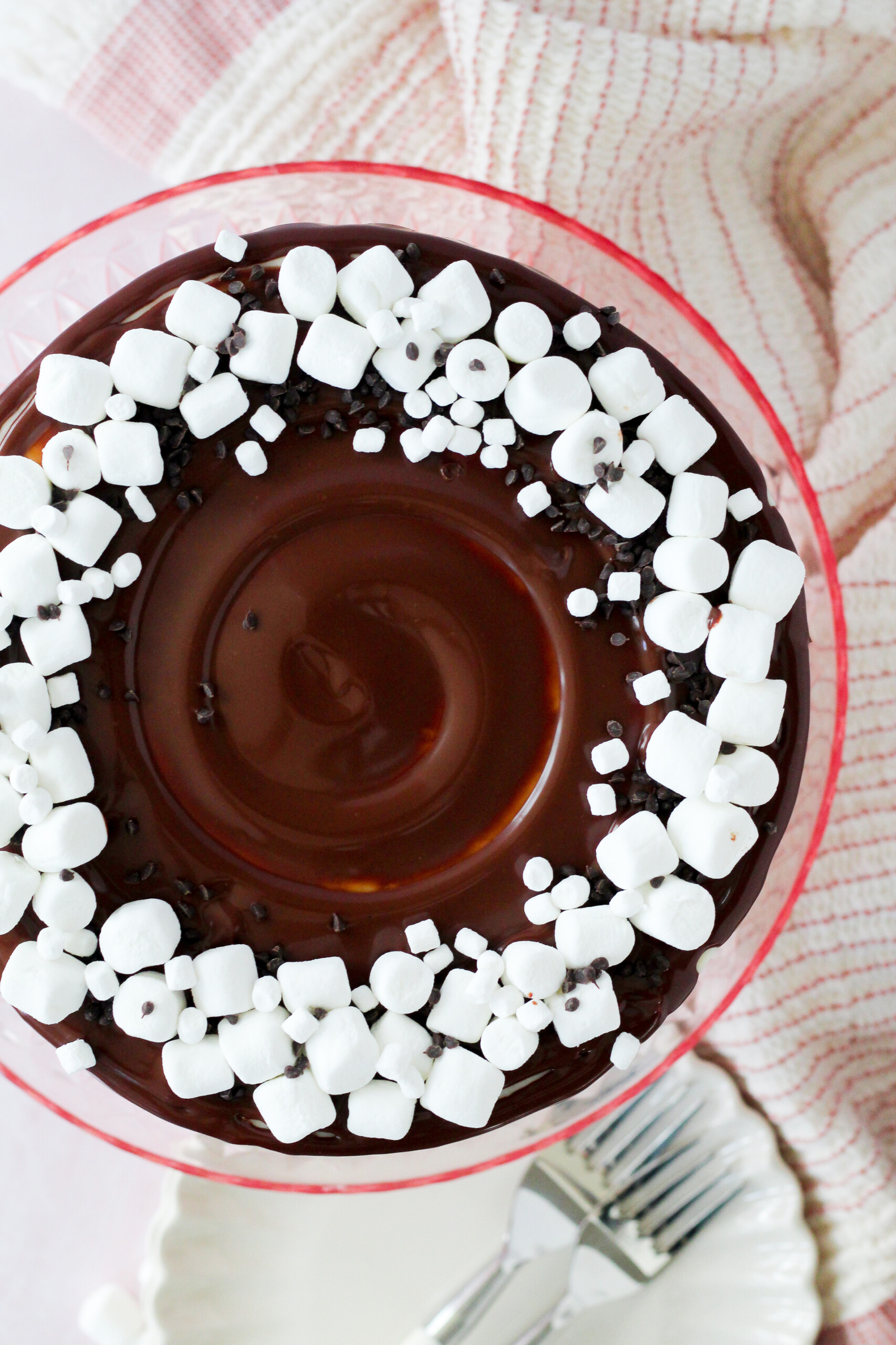 Top view of a cake with chocolate ganache and marshmallows on top.