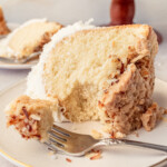 A slice of the famous Tom Cruise White Chocolate Coconut Bundt Cake on a white plate with a fork.