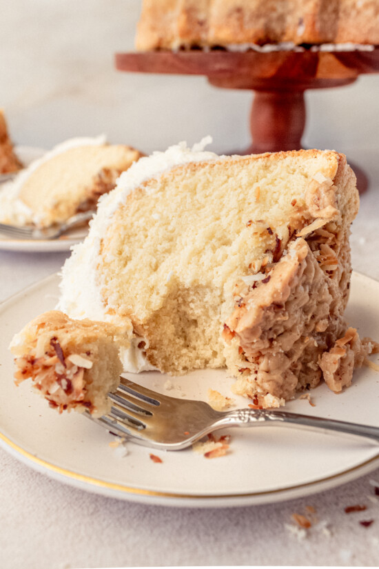 A slice of the famous Tom Cruise White Chocolate Coconut Bundt Cake on a white plate with a fork.