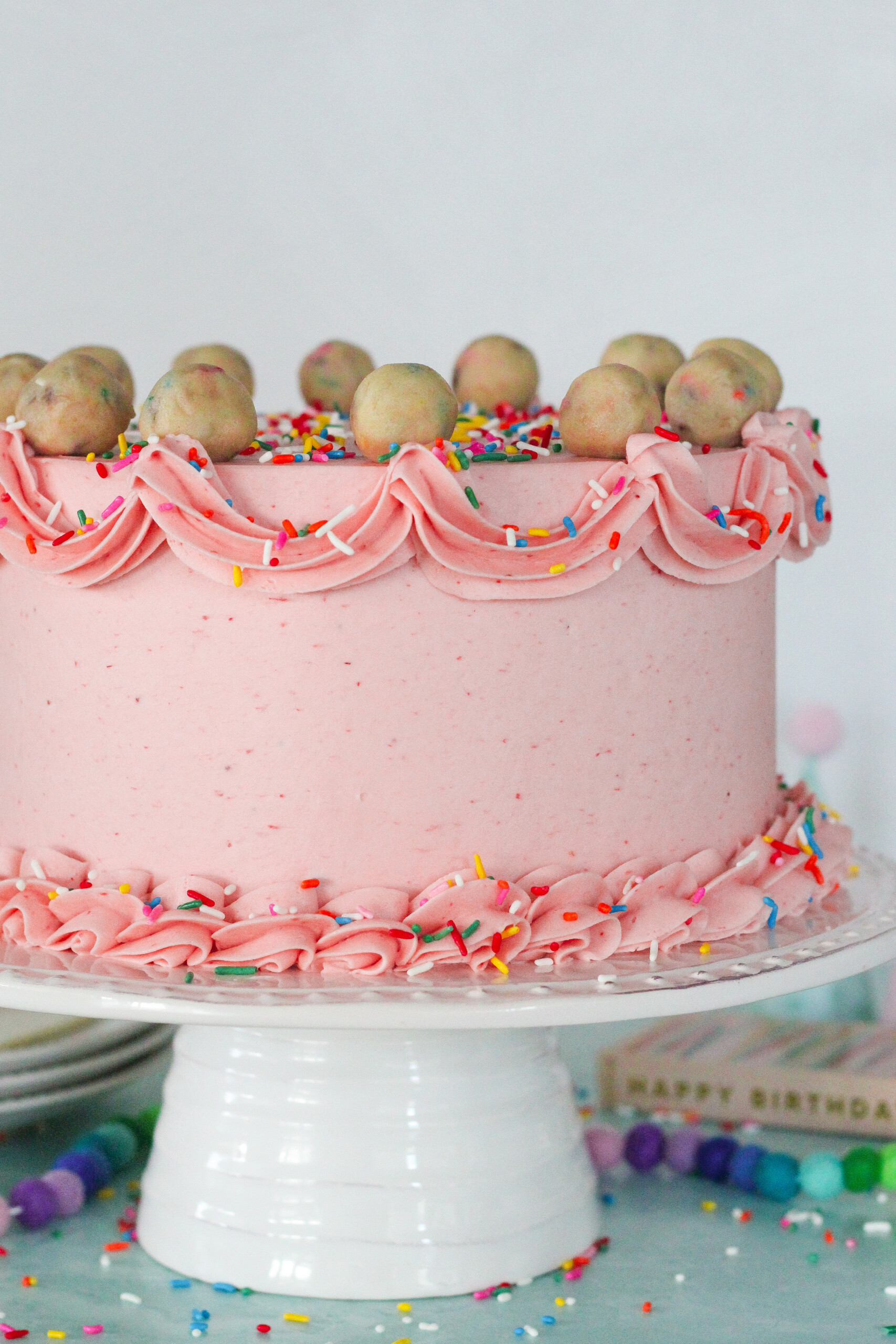 Pink cake with piping decorations on it.