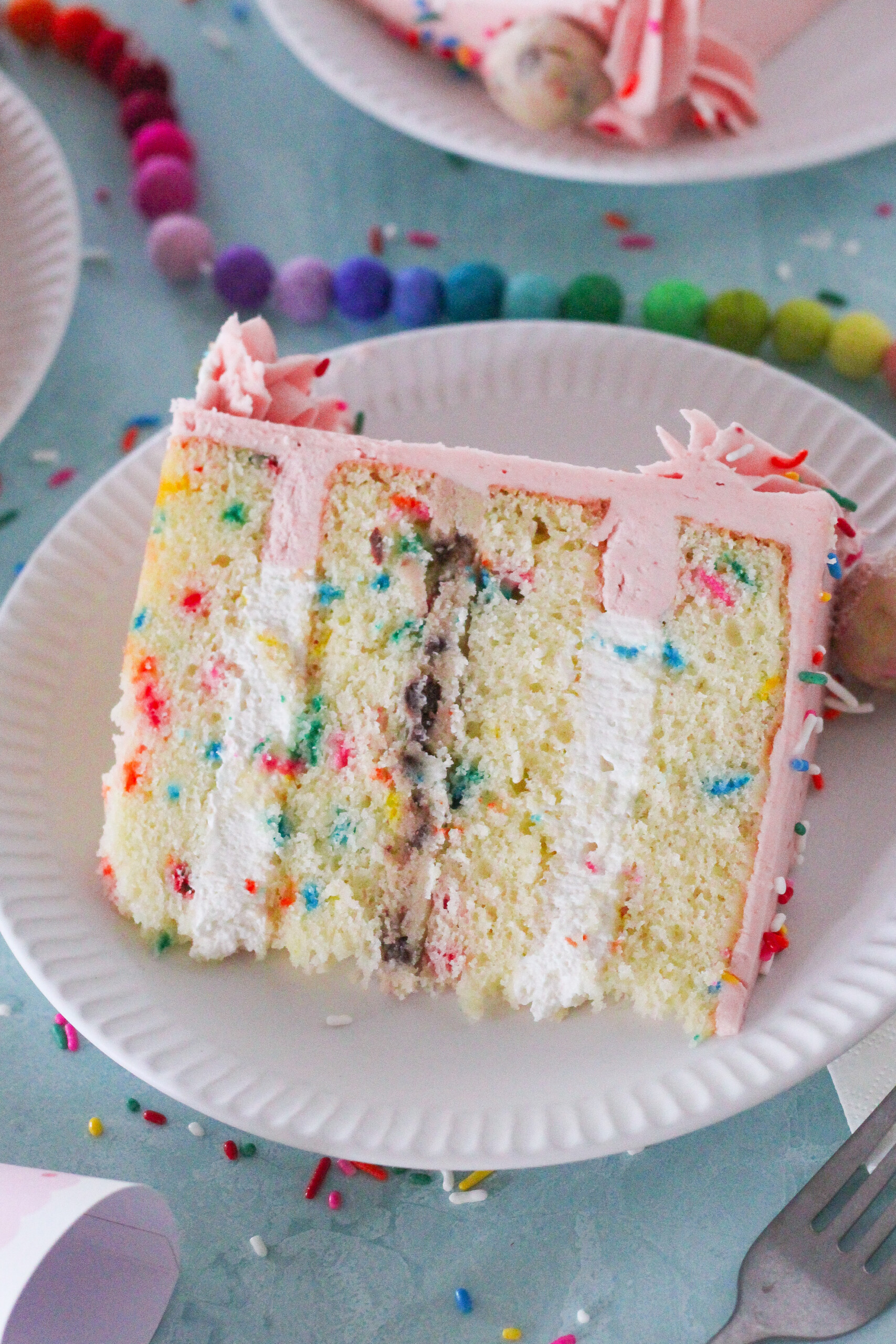 A slice of confetti cake on a plate with party decorations.
