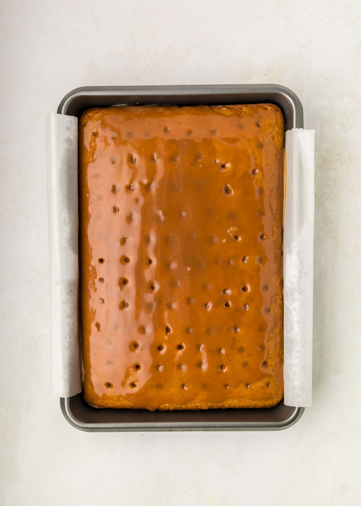 Pumpkin cake with holes in it and caramel on top.