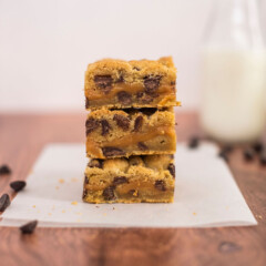 Three chocolate chip caramel bars stacked on a table.