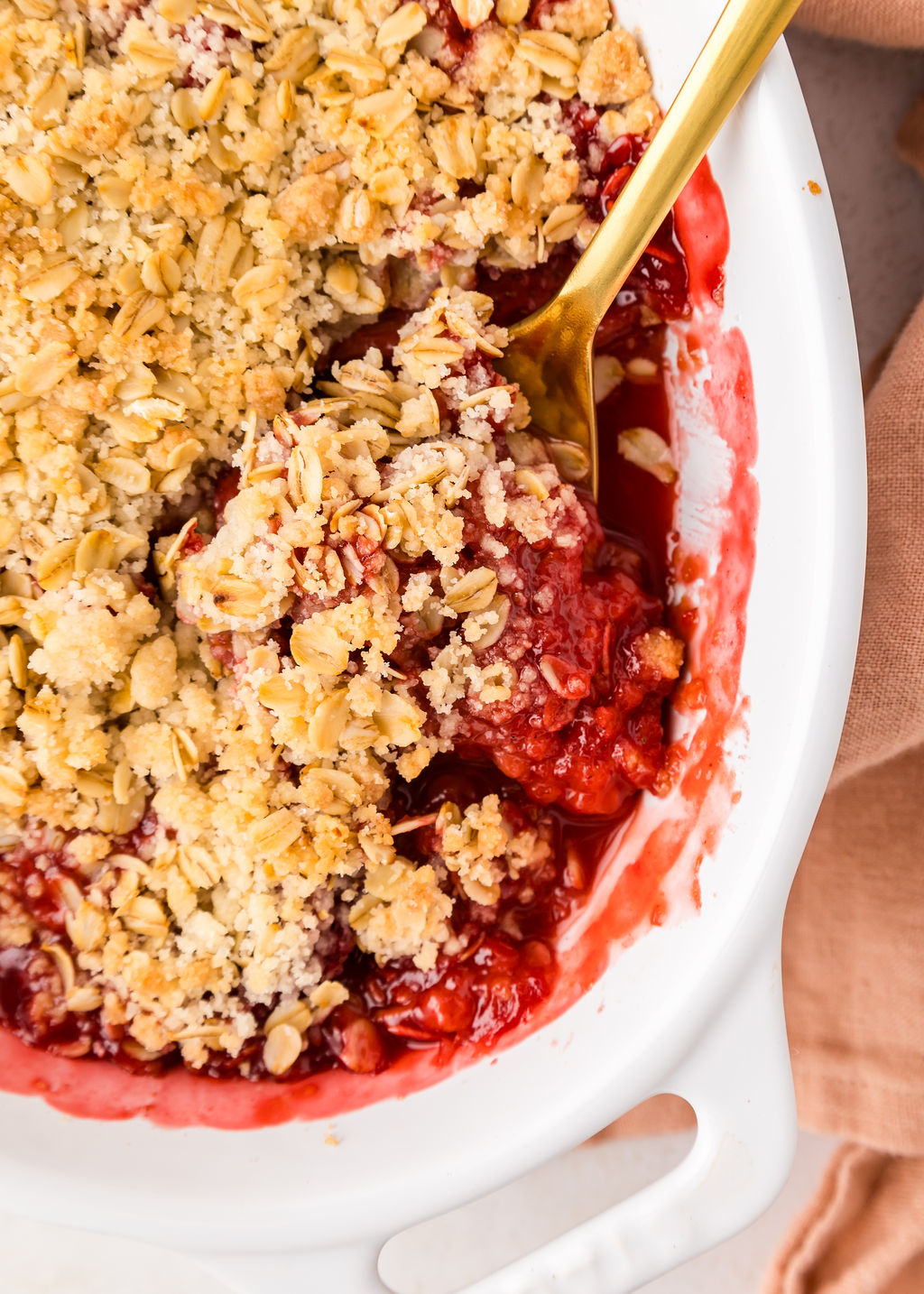 A spoon in a strawberry rhubarb crumble.