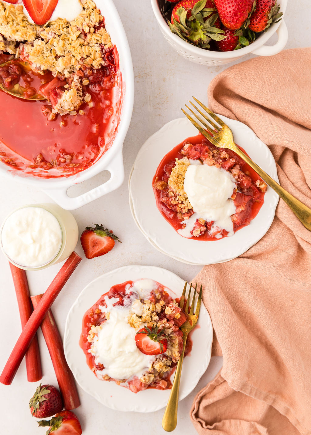 Strawberry Rhubarb Crumble on two plates with napkins and forks nearby.