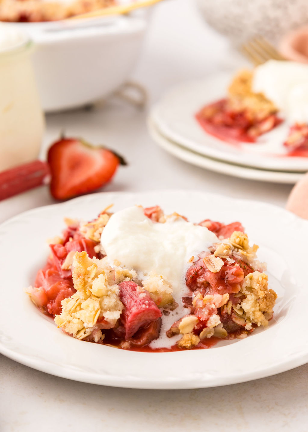 A plate with a strawberry rhubarb crumble serving on it. 