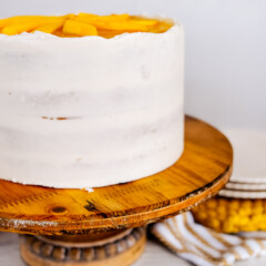 A Mango Cake on a wood cake stand.