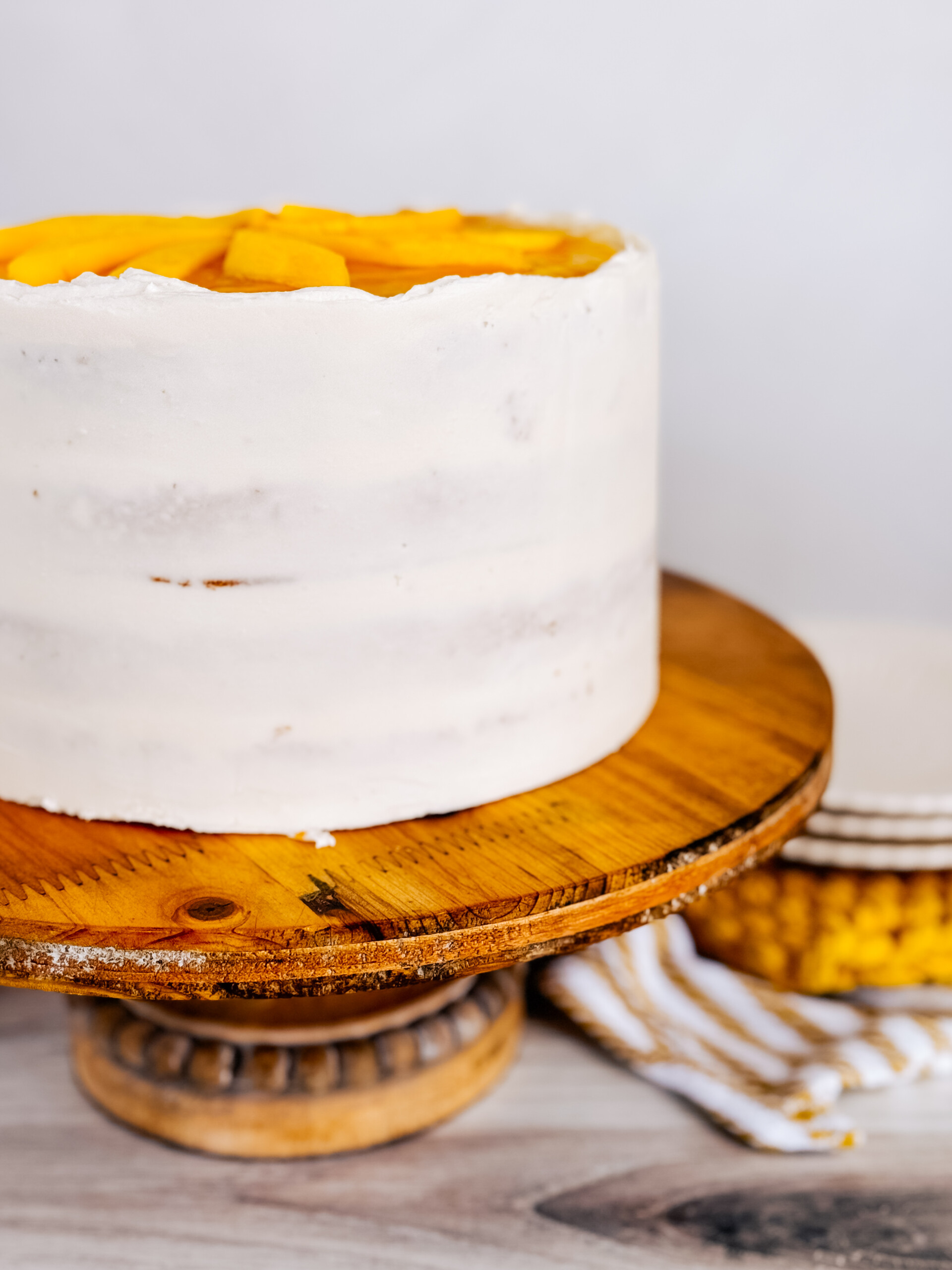 A Mango Cake on a wood cake stand.