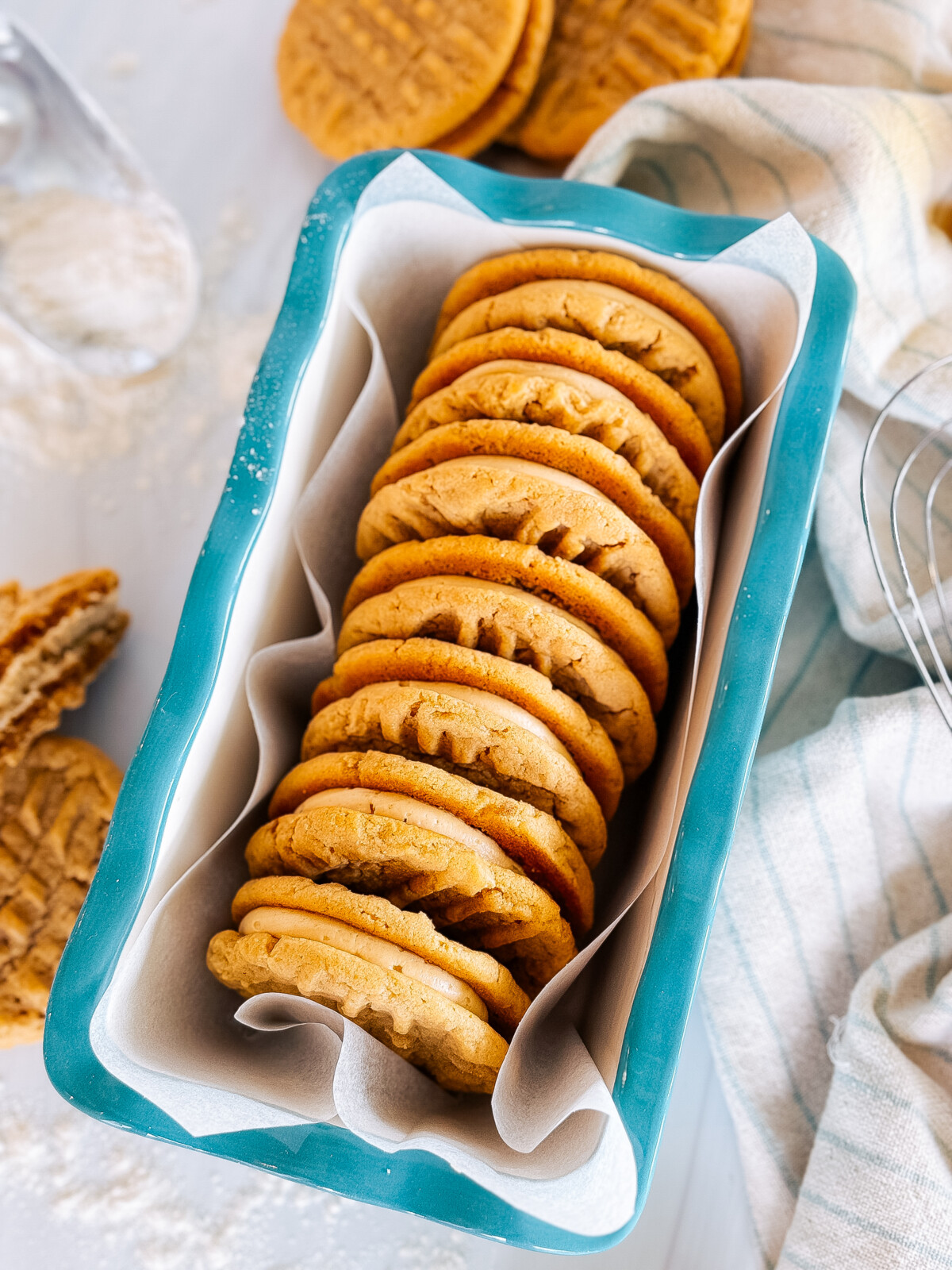 Peanut butter sandwich cookies in a bread pan with cookies next to it.