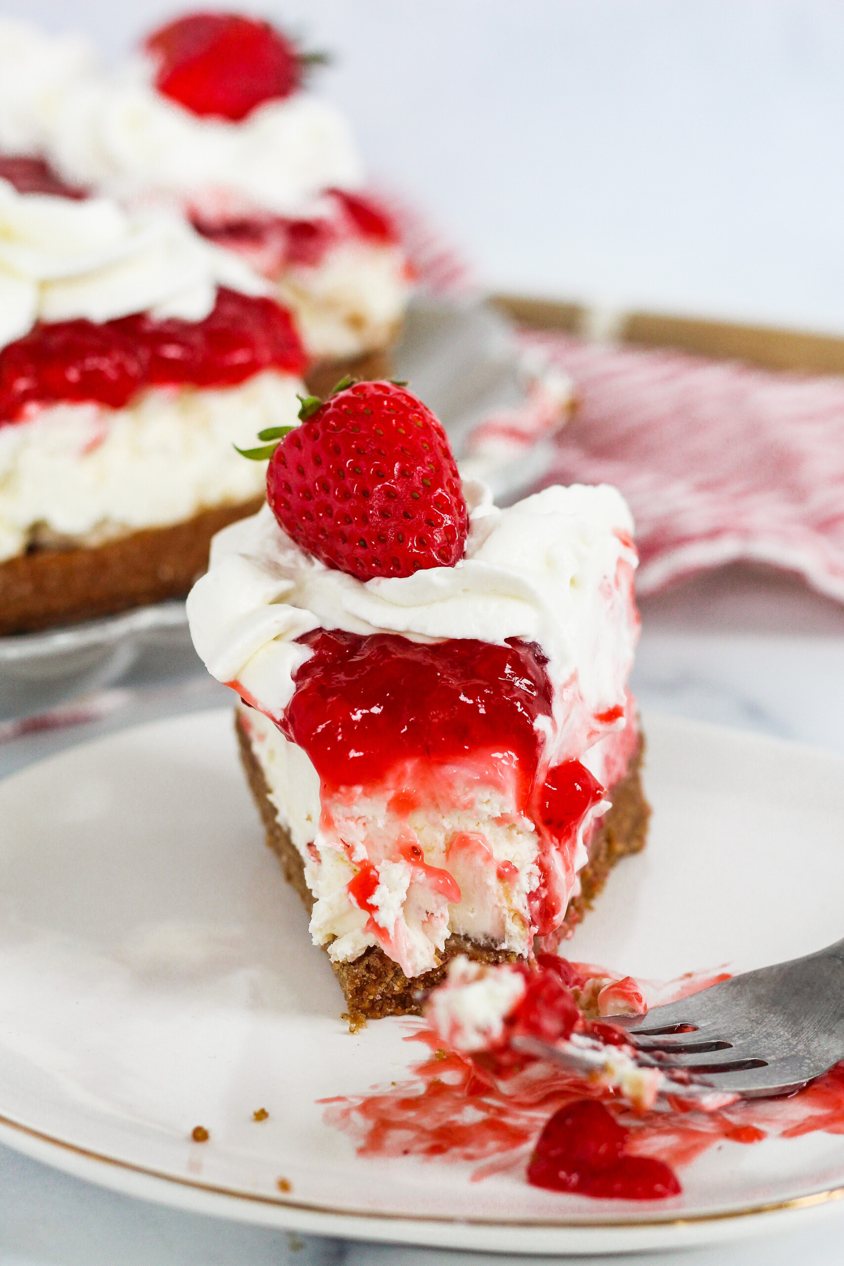 Slice of a no bake strawberry biscoff cheesecake on a plate.