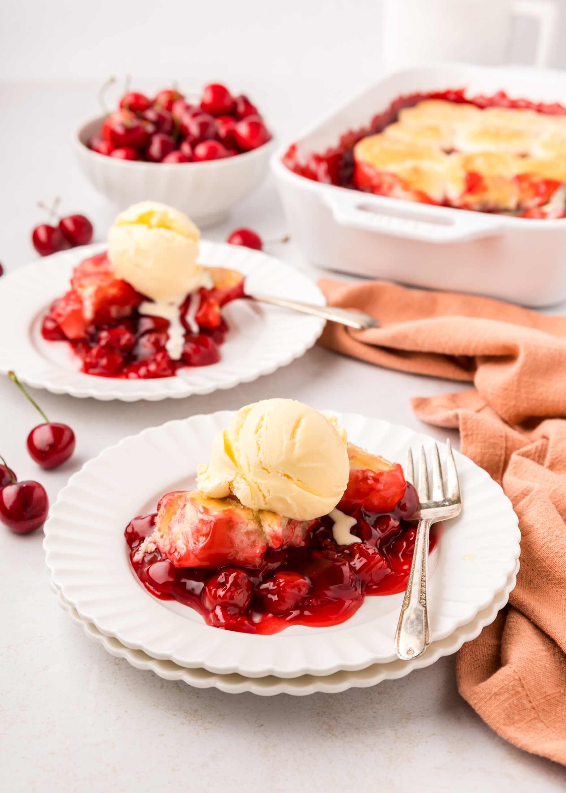 Cherry cobbler on plates with ice cream.