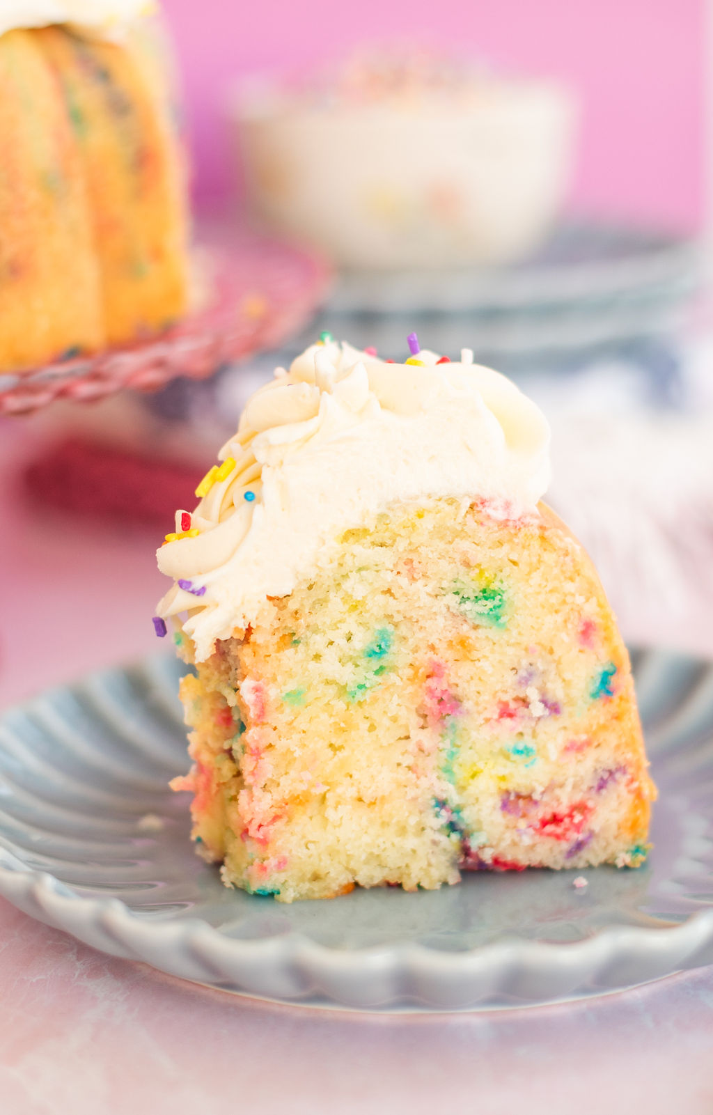 Slice of confetti cake on a blue scalloped plate.