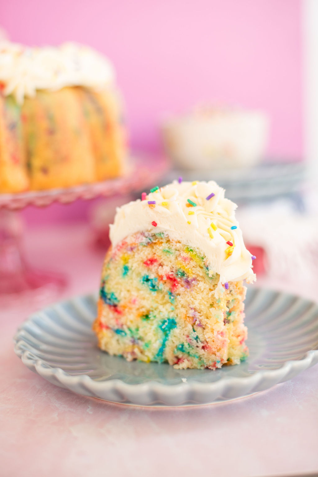 Slice of a confetti bundt cake on a blue plate.