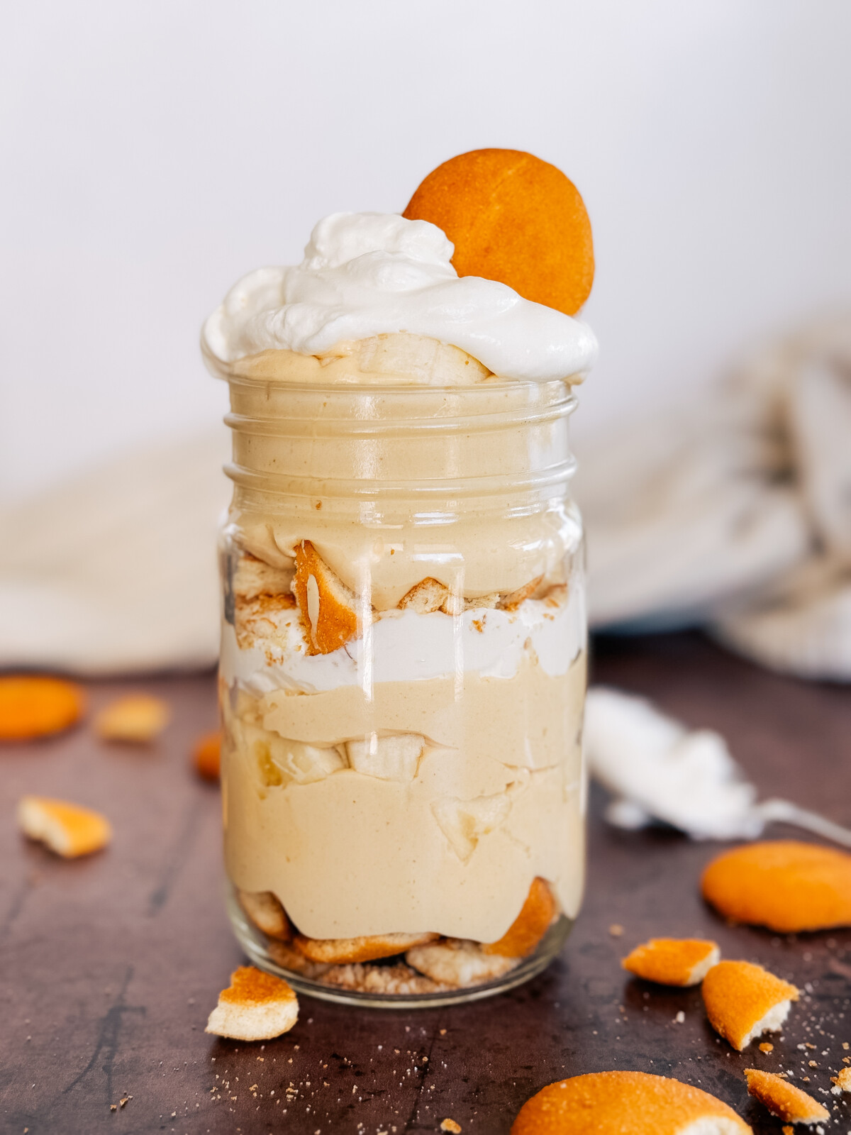 Peanut Butter Banana Cream Pudding layered in a mason jar with a cookie on top.