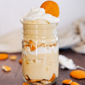 Peanut Butter Banana Cream Pudding layered in a mason jar with a cookie on top.