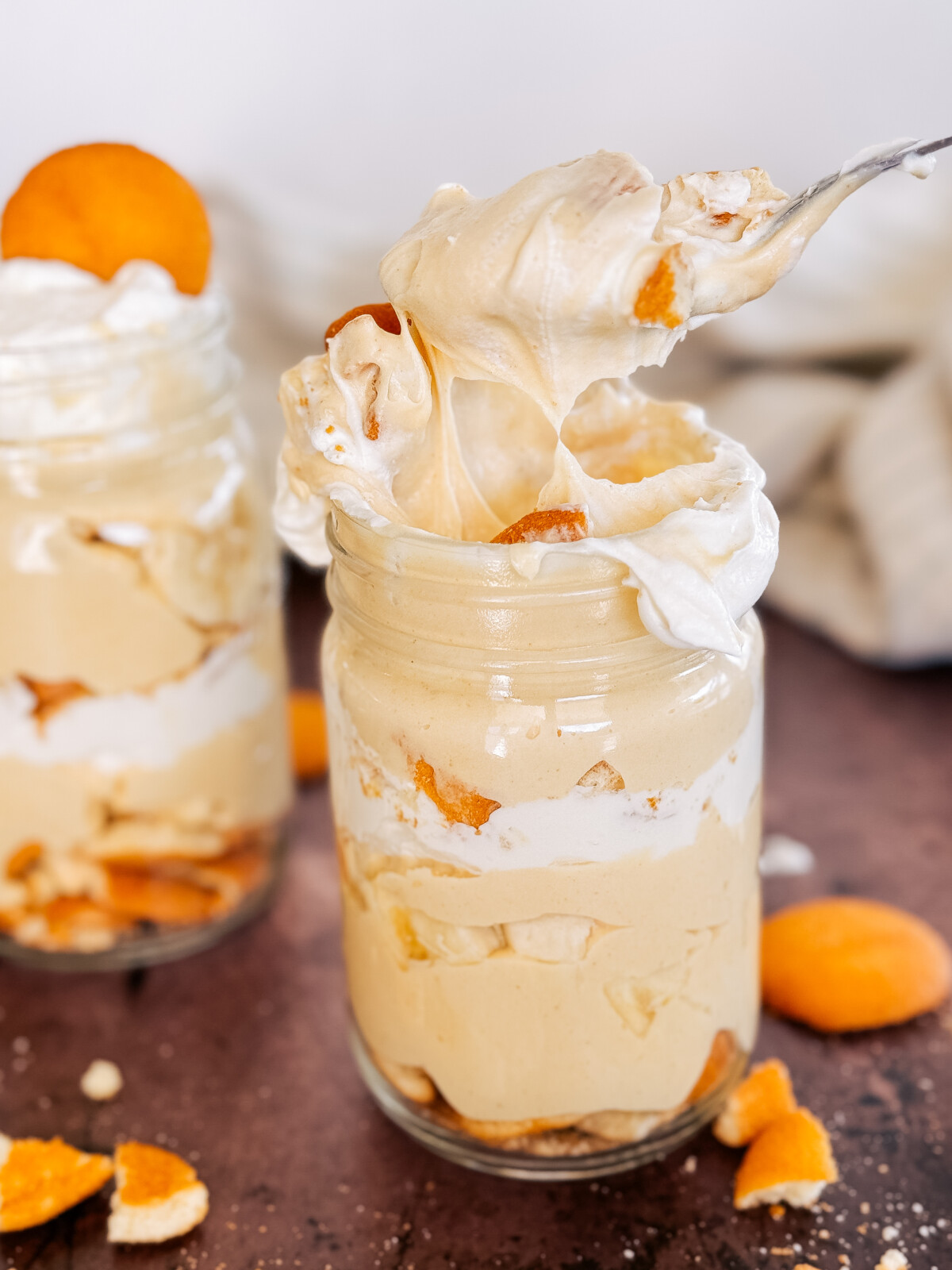 A spoon coming out of a mason jar of Peanut Butter Banana Cream pudding.