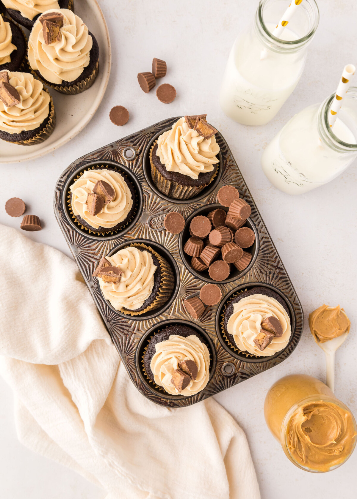 Chocolate peanut butter cupcakes in a cupcake pan with milk and peanut butter next to it.