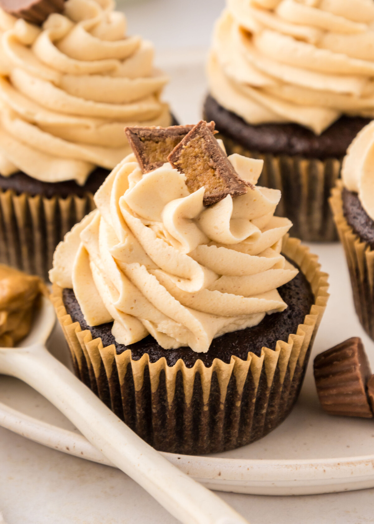 A chocolate cupcake in a yellow cupcake liner with peanut butter buttercream on top.