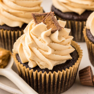 A chocolate cupcake in a yellow cupcake liner with peanut butter buttercream on top.