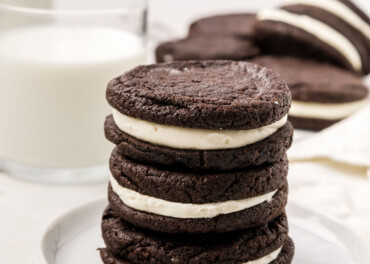 A stack of homemade Oreos with milk in a cup.