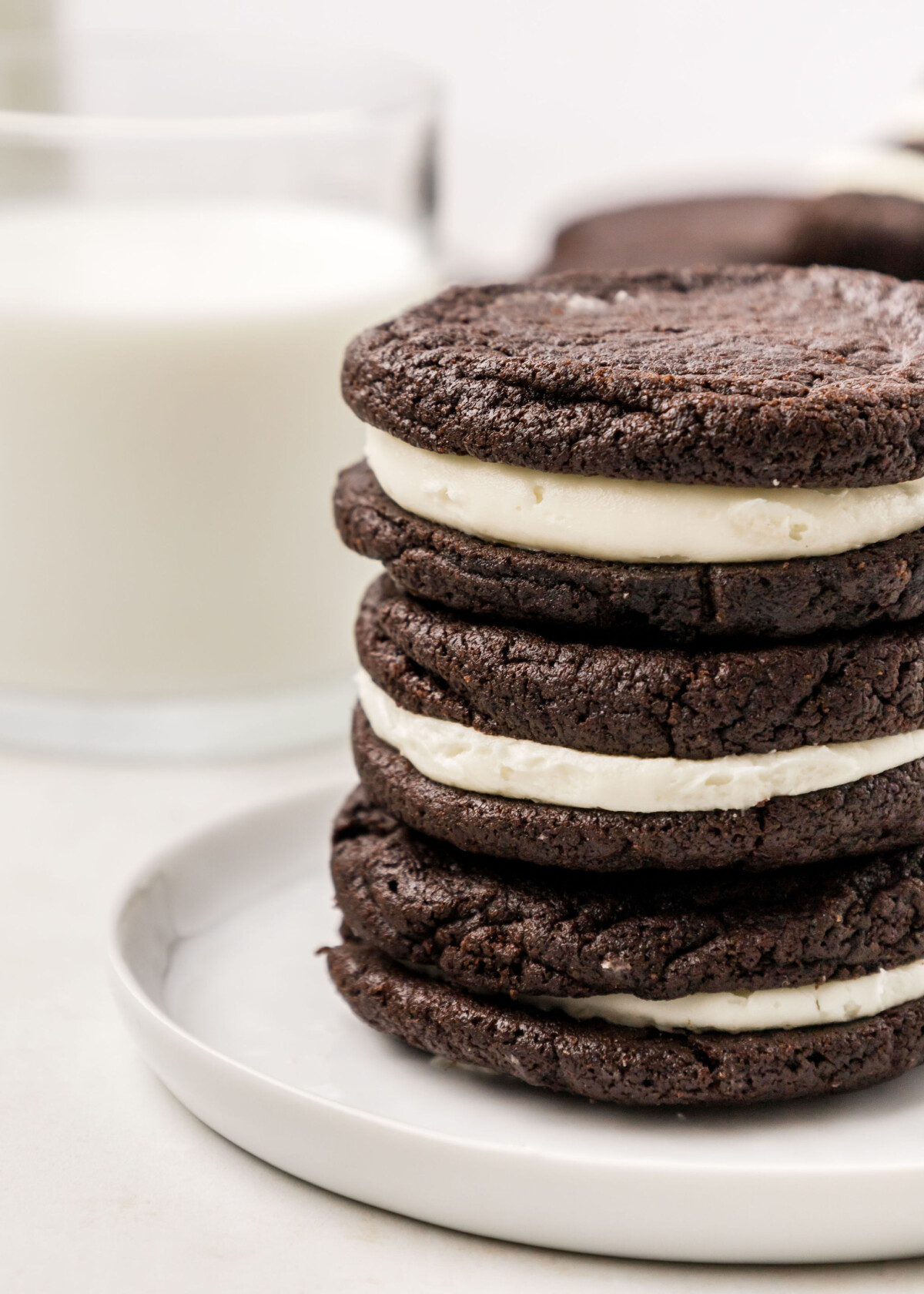 A stack of homemade Oreo cookies with a glass of milk.