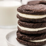 A stack of homemade Oreo cookies with a glass of milk.